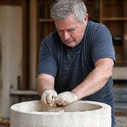 Master Stonemason Liam O'Connell meticulously carving a stone basin with traditional tools
